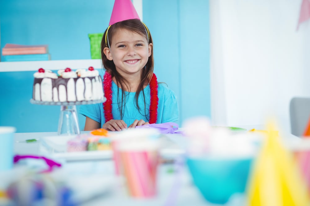 Smiling kid beside her birthday cake