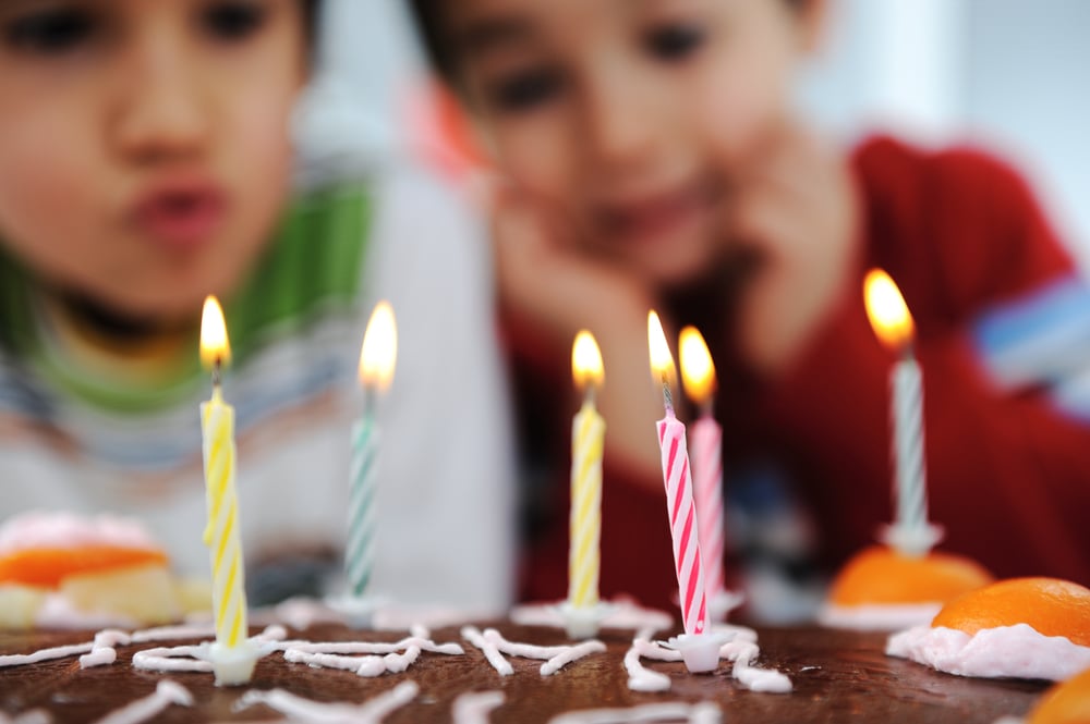 Two little boys blowing candles on cake, happy birthday party